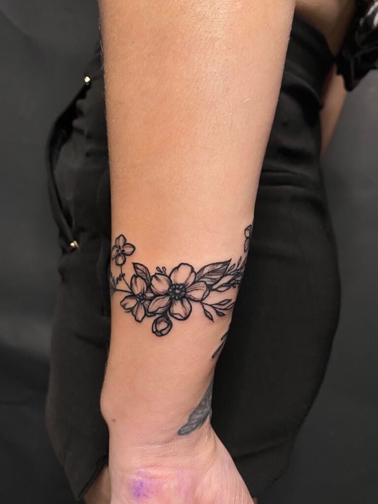 tattoo tatuaj tatuat de berea ana maria pe o fata pe mana incheietura antebrat cu flori frunze floare de cires bratra de flori bracelet