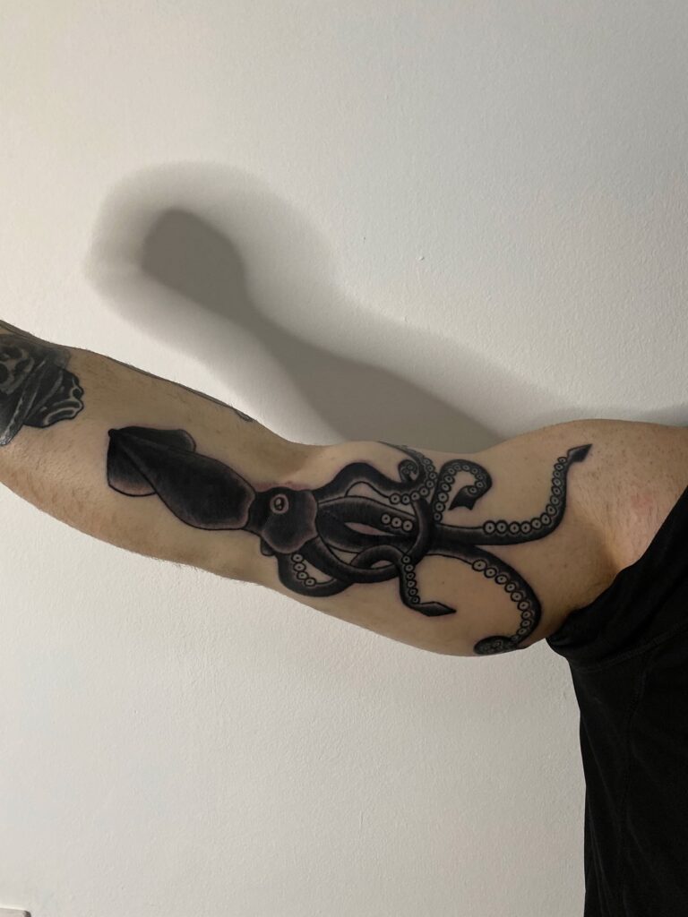 tattoo tatuaj de berea ana maria pe baiat boy pe mana brat cu caracatita in stil traditional alb negru tentacule